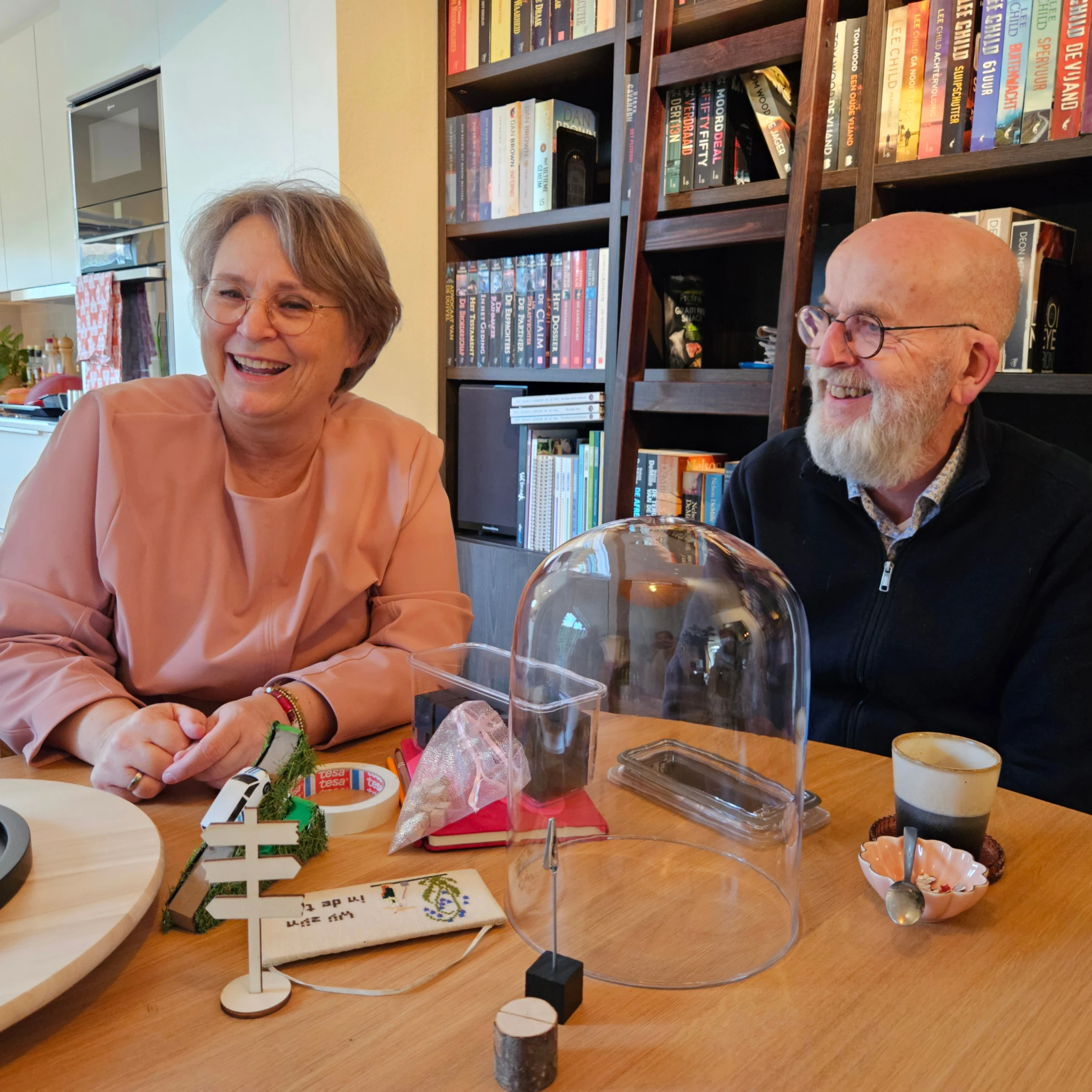Wendy en een gast lachen samen aan tafel, tussen een glazen stolp en een draaiplateau.