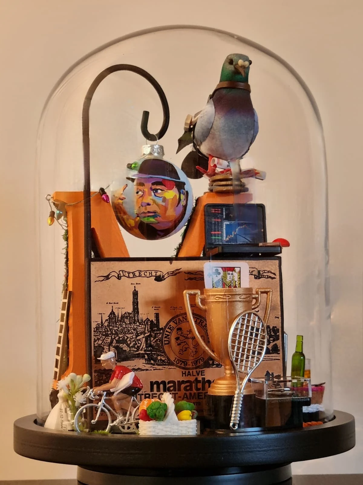 Stolp met een duif, een kerstbal met een portret, een houten letter M, een bord van de halve marathon Utrecht–Amersfoort, een beker, een tennisracket en een wielrennertje.