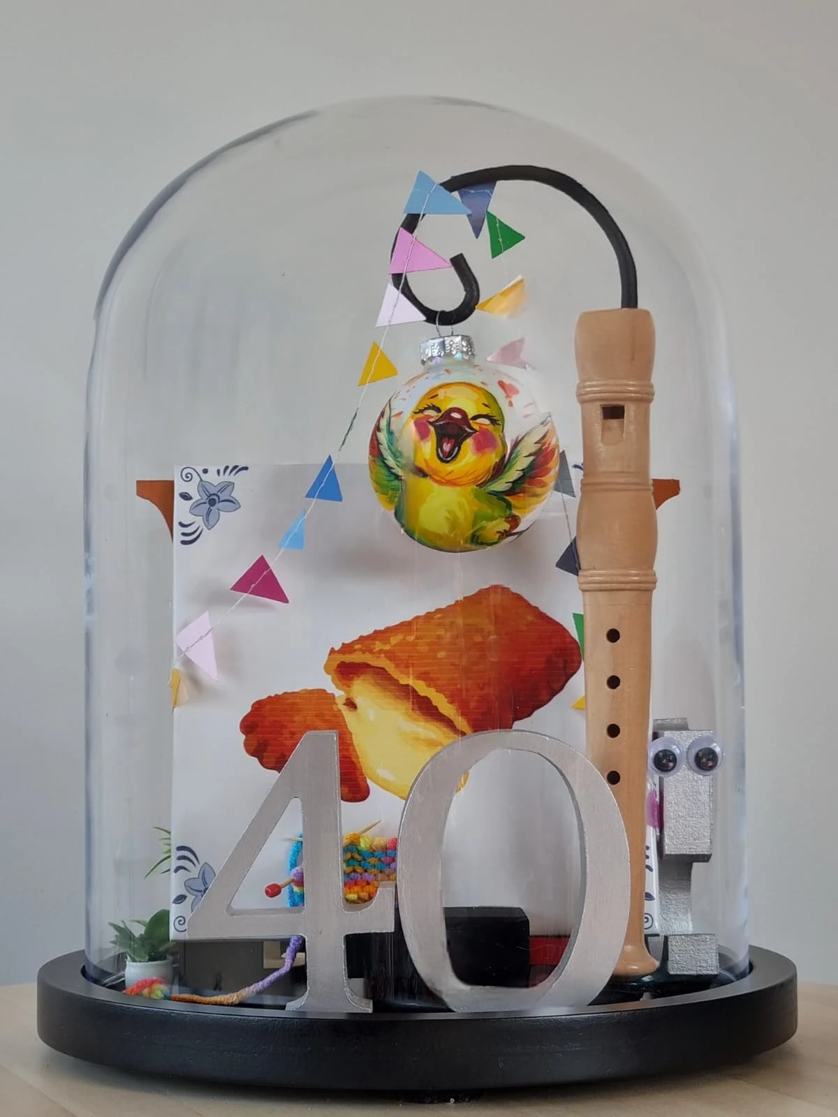 Stolp met een groot zilveren getal 40, een blokfluit, vlaggetjes en een kerstbal met een lachend vogeltje.