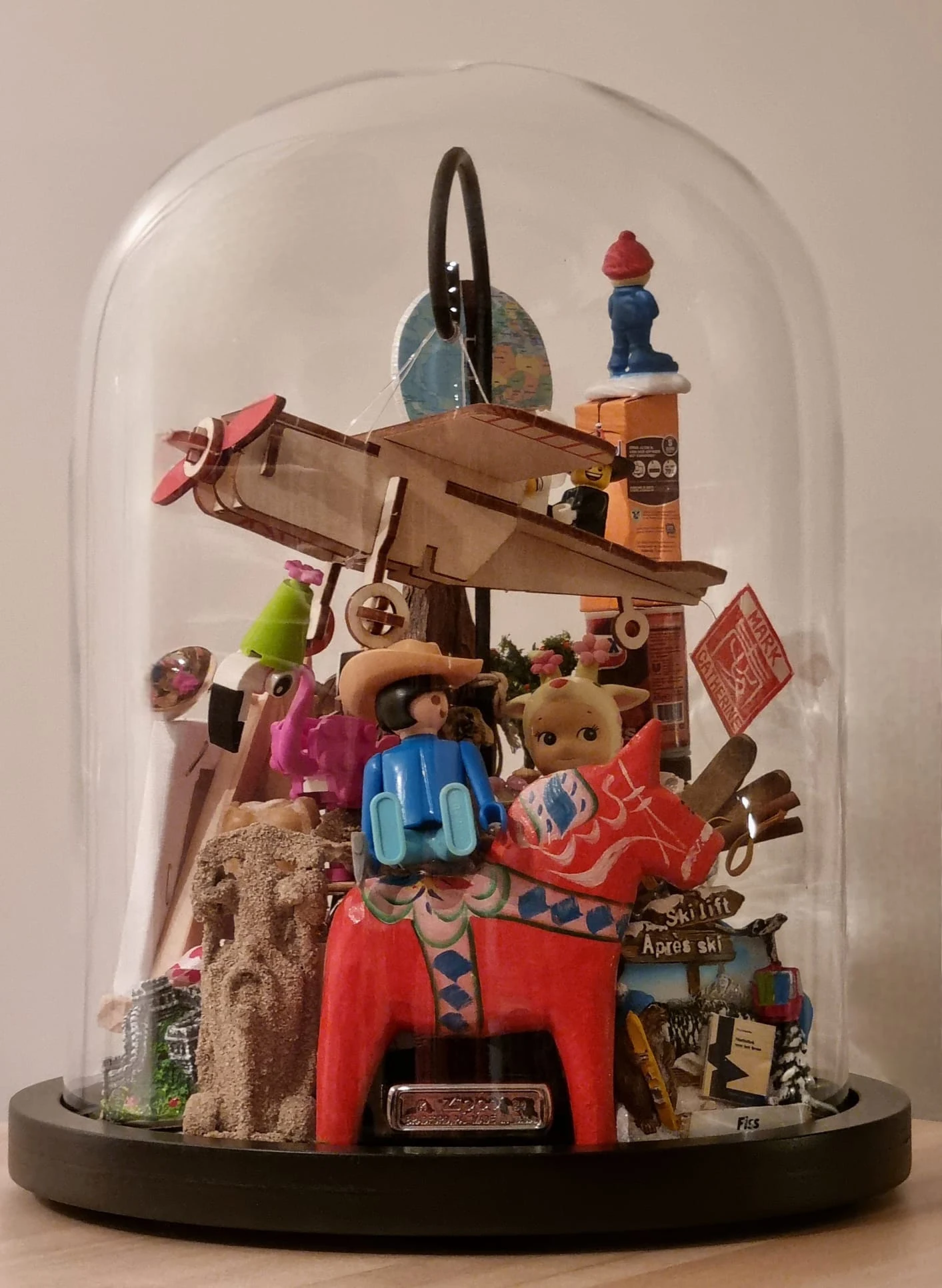 Stolp met een houten vliegtuigje, een rood Zweeds dalapaardje, een speelgoedpoppetje en allerlei souvenirs.